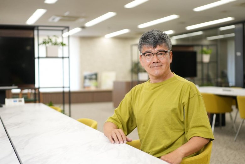 オフィスのテーブルに着席している人物。