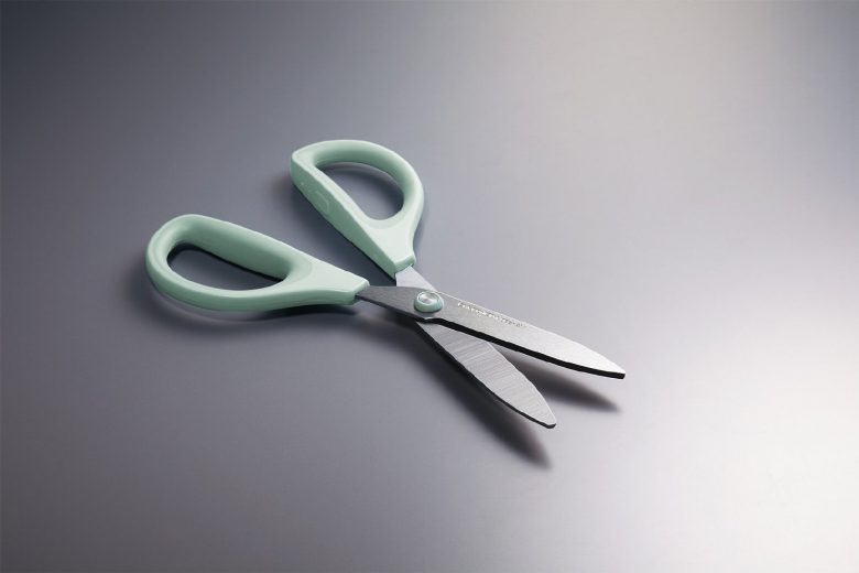 テーブルに置かれた、刃が開いた左右対称のハサミ。