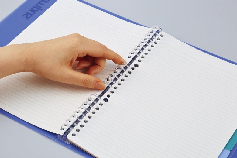 開いたバインダーの中心にあるリングの左側を2つの指で上下からつまんでいる。