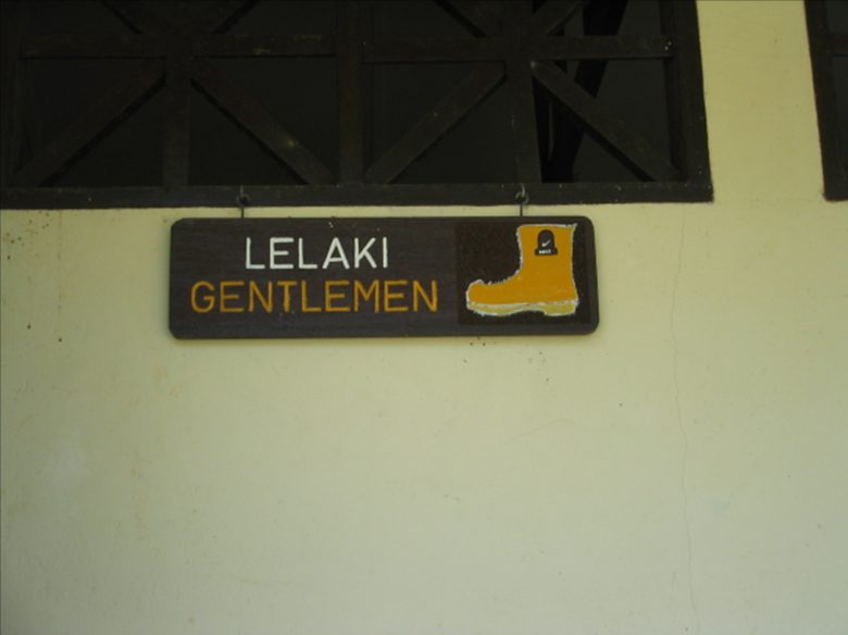 壁に掛けられた案内看板。「LELAKI」「GENTLEMEN」と書かれ、右側にブーツのイラストが描かれている。