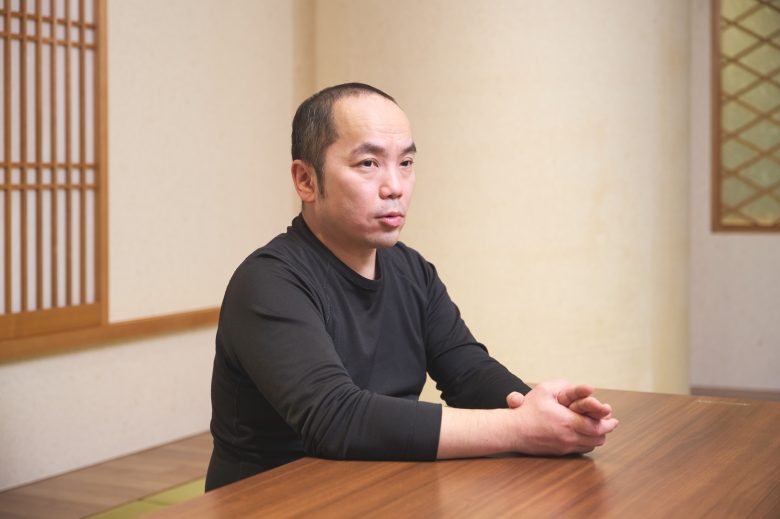 和室で、テーブルの上に両手を置きつつ話す羽山さん。